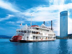 a large white boat on the water with buildings at Lake Biwa Otsu Prince Hotel in Otsu