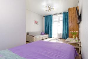 a bedroom with a purple bed and a couch at Красотка на Нурлы Жол in Astana