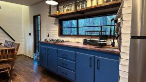 a kitchen with blue cabinets and a large window at Cabañas Corazón del Bosque in Tapalpa