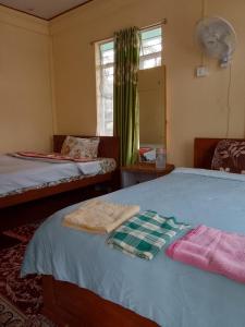 a bedroom with two beds and a window at Pt khongknaw homestay in Mawlynnong