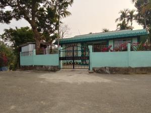 a blue building with a gate and a tree at Pt khongknaw homestay in Mawlynnong
