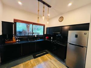 a kitchen with black cabinets and a stainless steel refrigerator at RW Homestay in Wegala +59 photos
