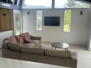 a living room with a couch and a flat screen tv at Totara Bach in Tata Beach