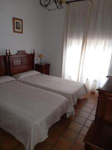 a bedroom with two beds with white sheets and a window at Bungalows Los Álamos de El Pedroso in El Pedroso