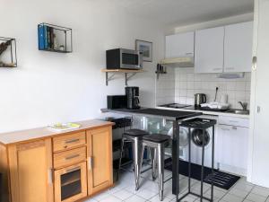 a kitchen with white cabinets and bar stools at Studio cosy avec balcon, idéal pour 2 pers, Chatelaillon-Plage - FR-1-706-32 in Châtelaillon-Plage
