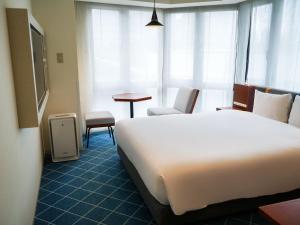 a hotel room with a bed and a table and chairs at Rembrandt Style Yokohama Sakuragicho in Yokohama