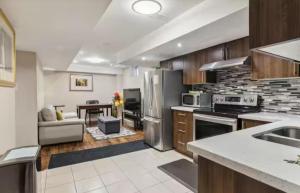 a kitchen with stainless steel appliances and a living room at Comfortable & Cozy 2BR Hideaway Basement Appartment in Brampton