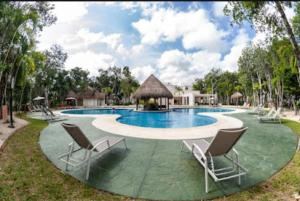 a pool at a resort with chairs and a gazebo at Selva escondida in Puerto Morelos