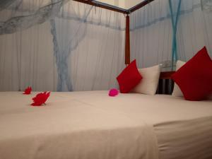 un lit avec des oreillers rouges et des fleurs rouges dessus dans l'établissement Mountain Heaven inn, à Mirissa