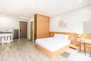 a bedroom with a white bed and a kitchen at Fame Apartment in Dong Hoi