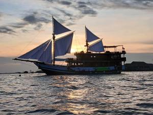 a sail boat sitting in the water at sunset at Gallia Phinisi Batam in Nagoya