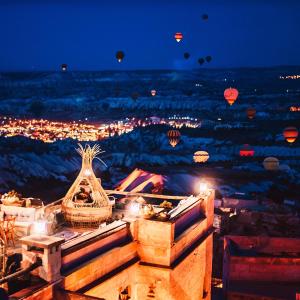 ウチヒサールにあるロックス カッパドキアの夜の熱気球付きの市街の景色