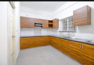 a kitchen with wooden cabinets and a sink at SLN Suites, Near Baptist Hospital, Hebbala in Bengaluru +11 photos