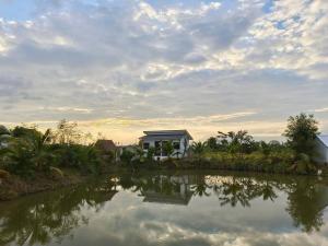 a house by the water with a cloudy sky at FarmStay Tawanchai ฟาร์มสุขตะวันฉาย YS in Ban Fak Huai +10 photos