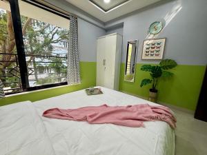 a bedroom with a white bed with green walls and a window at Modern 2 BR Bandra Trendy Location in Mumbai