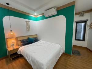 a bedroom with a bed with a green accent wall at HomestayHoangYen in Phường Sáu