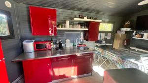 a kitchen with red cabinets and a red microwave at La yourte de Nîmes, sauna, spa , jacuzzi piscine et aire de jeux privatif in Caveirac