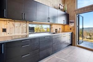 a kitchen with wooden cabinets and a large window at The Holiday - Panorama Lodge in Lampeland