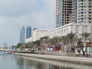 a city with tall buildings and a body of water at Muscat Tower in Sharjah
