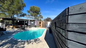 a swimming pool next to a wooden fence at La yourte de Nîmes, sauna, spa , jacuzzi piscine et aire de jeux privatif in Caveirac