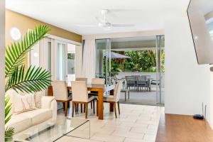 una sala da pranzo e un soggiorno con tavolo e sedie di Belle Escapes Drift Beachfront Resort Suite 3207 a Palm Cove