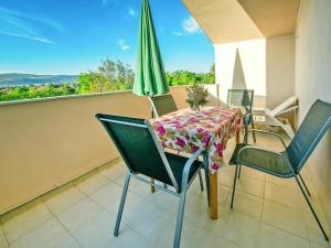 stół z krzesłami i zielony parasol na balkonie w obiekcie Apartment in Starigrad Paklenica w mieście Starigrad-Paklenica