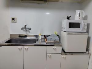 a kitchen with a sink and a microwave at Sun and Moonホテル302 in Tokyo