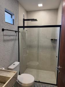 a bathroom with a toilet and a glass shower at Casa en Milagres com piscina 600 metros da praia in São Miguel dos Milagres