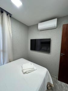 a bedroom with a bed with a television and towels at Casa en Milagres com piscina 600 metros da praia in São Miguel dos Milagres +58 photos