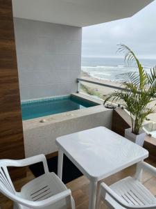 een witte tafel en stoelen in een kamer met een zwembad bij Apartment Rosi Beach & Pool Punta Hermosa in Punta Hermosa