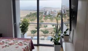 een slaapkamer met een groot raam met potplanten bij Apartment Rosi Beach & Pool Punta Hermosa in Punta Hermosa +12 foto's