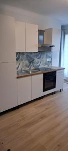 a kitchen with white cabinets and a stove top oven at Grand studio Sophie rénové avec goût Wi-Fi balcon parking 50m des cures in Amélie-les-Bains-Palalda