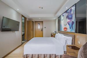 - une chambre avec un grand lit blanc et une télévision à écran plat dans l'établissement Insail Hotels (Pazhou Exhibition Center KeCun Metro Station Dunhe Road Branch Guangzhou), à Canton