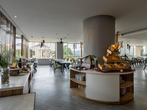 a restaurant with tables and chairs and a counter with food at Nemuru Grand Bhuvana Ciawi in Bogor