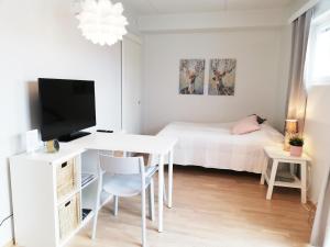 a white room with a bed and a desk with a tv at Kotimaailma - Modern studio in Vaasa citycenter, Kirjastokatu in Vaasa