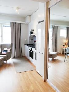 a kitchen with white appliances and a living room at Kotimaailma - Modern studio in Vaasa citycenter, Kirjastokatu in Vaasa