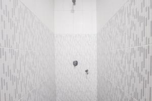 a bathroom with a shower with white tile at Urbanview Hotel Syariah at Rihlah Homestay Batam in Kangboi
