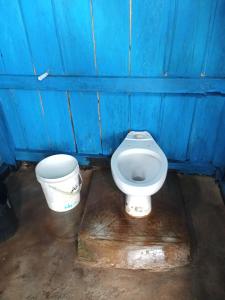 une salle de bain bleue avec des toilettes et un seau dans l'établissement Warfanin Homestay, à Pulau Gam