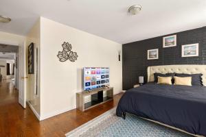 a bedroom with a bed and a black accent wall at Newark Gem Pearl 3BR, 2BA - Sleeps 10 - Walk to Prudential Center and Newark Penn Station, Near EWR and American Dream Mall, includes WiFi - Laundry - Backyard - Gym in Newark +19 photos