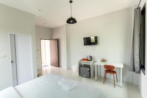 a white bedroom with a white bed and a table and a chair at เค้ง Kheng Chanthaburi in Chanthaburi