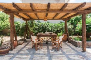 eine hölzerne Pergola mit Tisch und Stühlen auf einer Terrasse in der Unterkunft Cottage by the Sea in Vathy Methana in Megalochori