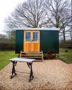 a bench in front of a tiny house with a cart at Mollies Hut in Frome