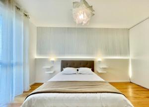 a bedroom with a large bed and a chandelier at ParcAppart 5 - Terrasse - Parking - Netflix in Lanester
