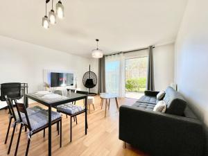 a living room with a black couch and a table at ParcAppart 5 - Terrasse - Parking - Netflix in Lanester