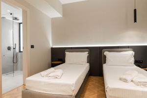 two beds in a room with a shower at SASSO Hotel in Vlorë