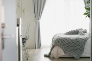 a bedroom with a bed with a gray blanket on it at 5B Guest House INFINITY in Naha