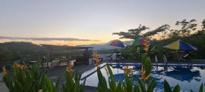 a swimming pool with umbrellas and a sunset in the background at CBHResort Agrofarm in Kampong Benchah Tualang