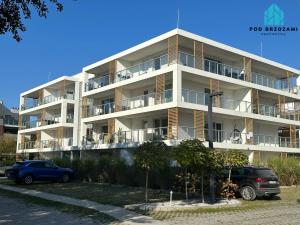 an apartment building with cars parked in front of it at Pod Brzozami Apartamenty Gąski in Gąski