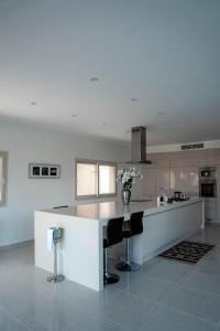 Caves Beach Resort Adults Only في الغردقة: مطبخ مع كونتر ابيض وبعض الكراسي