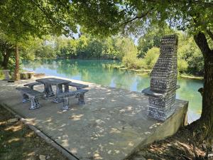 a picnic table and bench next to a river at Villa AS in Bihać